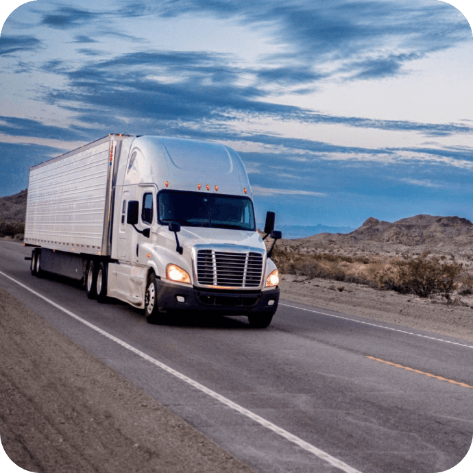 white semi truck driving on a two lane highway in the desert